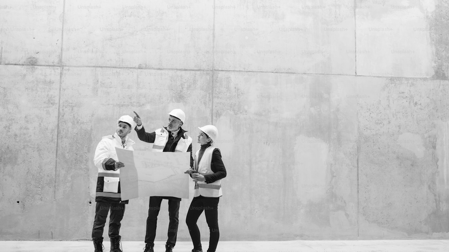 Three persons in worker clothing looking at a plan together